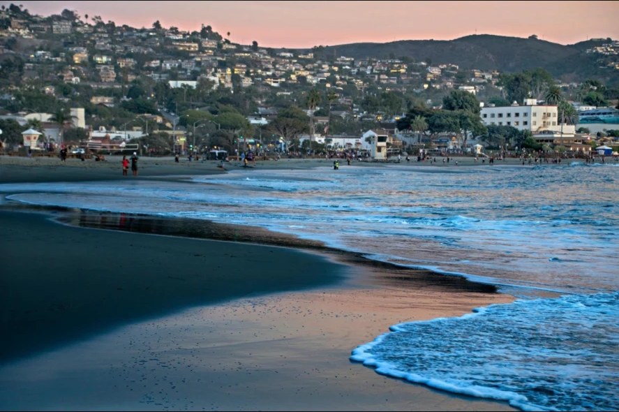 Main Beach at dusk with hillside lights above the shoreline