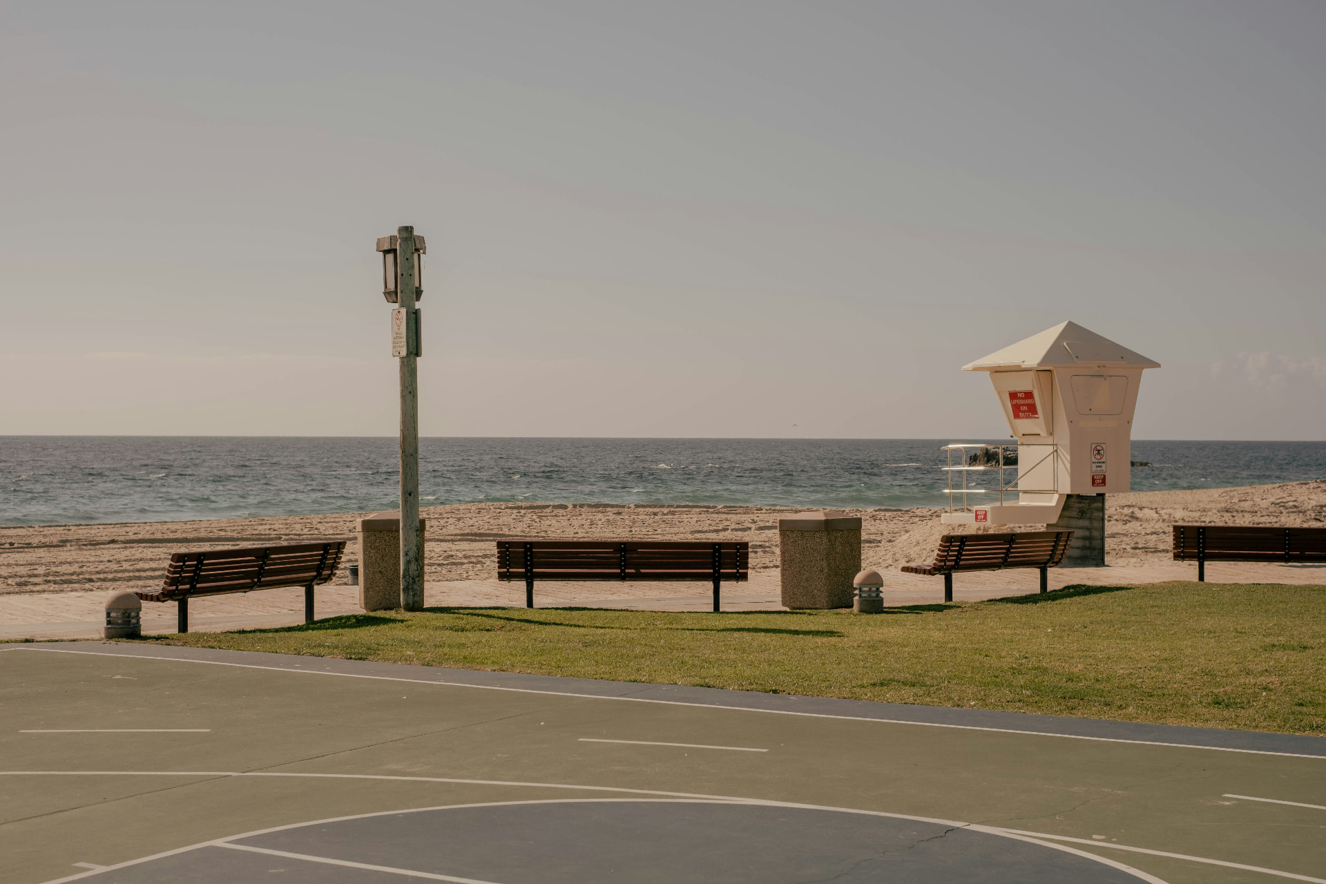 Lifeguard tower, benches and the boardwalk basketball court at Main Beach with the Pacific behind