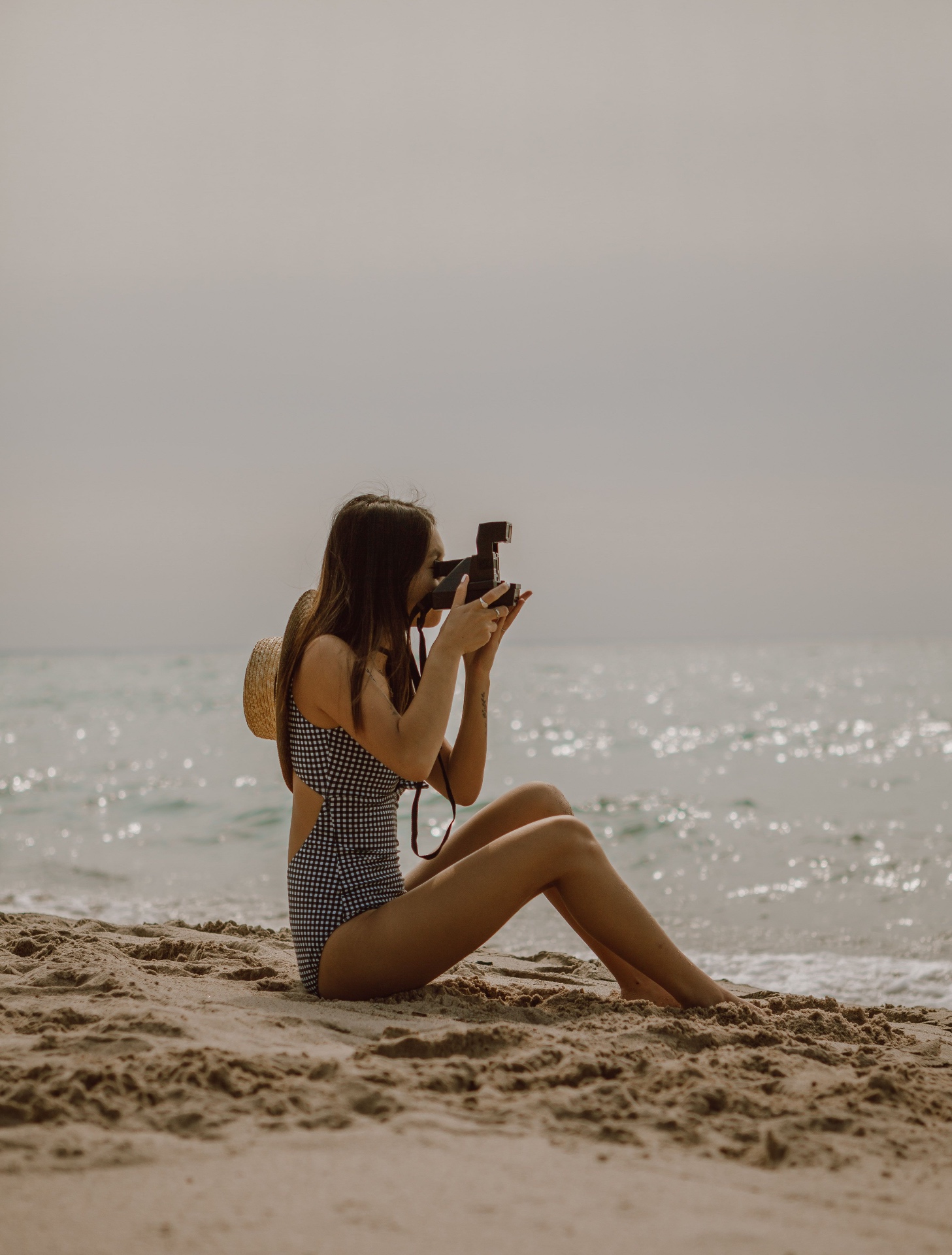 Woman with a vintage camera photographing the shoreline from the sand
