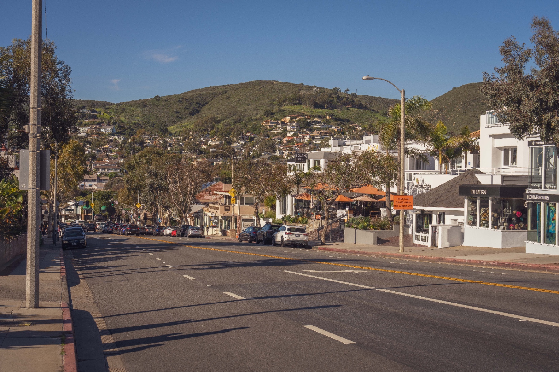 Coast Highway through the Laguna Beach village with galleries and green hills behind